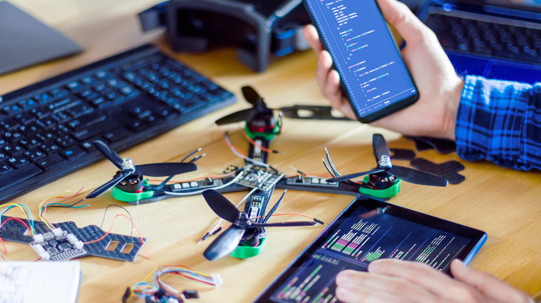 Person inputting code into smartphone while working on drone