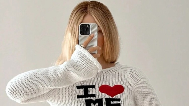 Model wearing a sweater taking a selfie