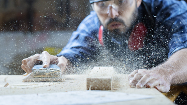 Man blowing away debris from wood table