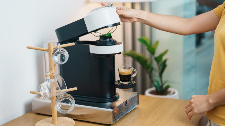 Person raising lid on pod coffee maker