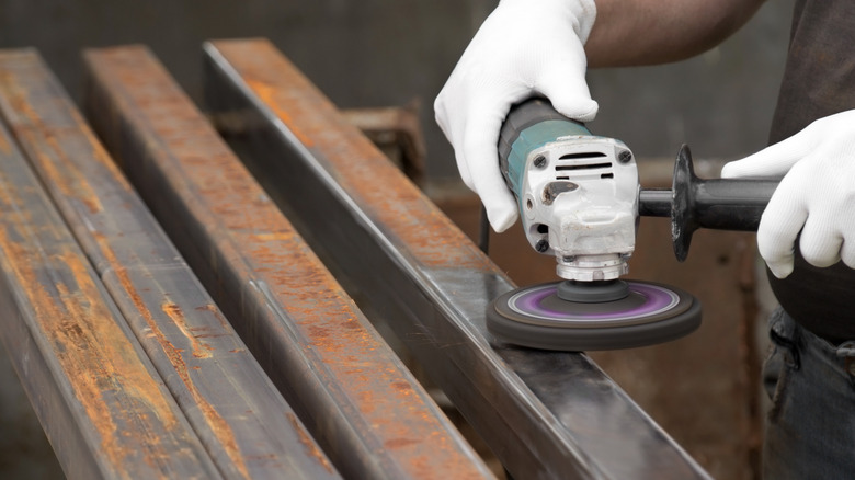 Man using power grinder on metal tubing