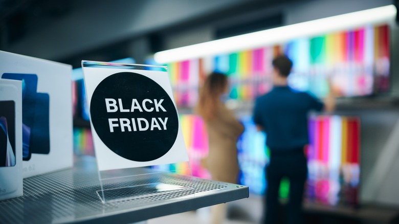 Black Friday sign in front of woman looking at different TVs