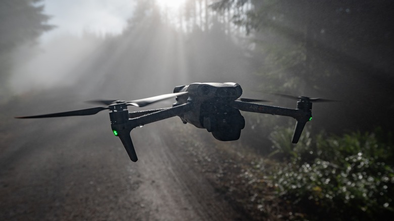 DJI Air 3S flying through rays of light in a misty forest.