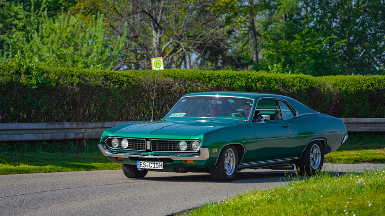 A first generation Ford Torino in green, front 3/4 view, driving