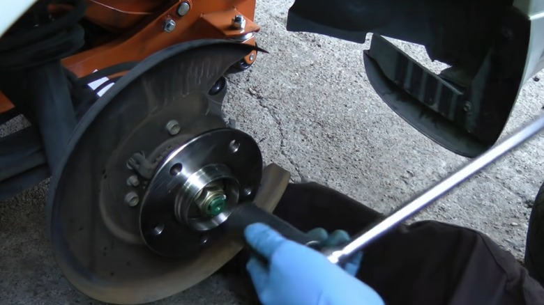 A person performing a DIY wheel bearing replacement