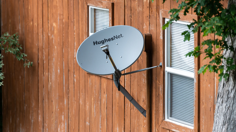 Satellite dish with HughesNet name on the side of the house