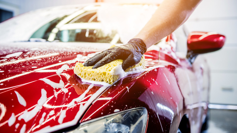 Someone washing their car with a sponge and soap