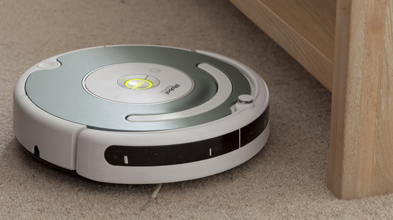 A Roomba vacuuming a shoelace off of the floor