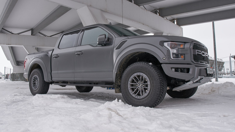 A gray Ford F-150 Raptor in the snow.