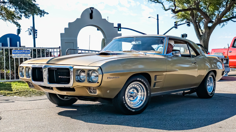 A gold Pontiac Firebird at an auto show