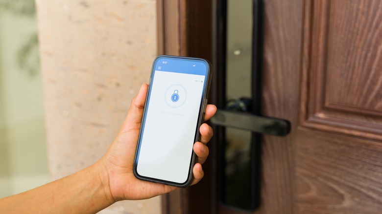 Person holding a smartphone up to a smart lock