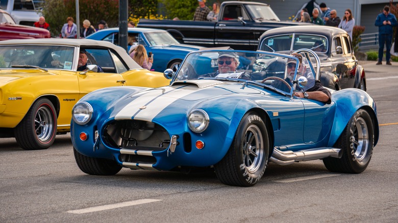 A blue Shelby Cobra driving down a road