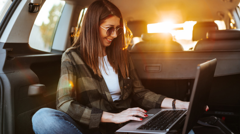 woman working on laptop in car trunk