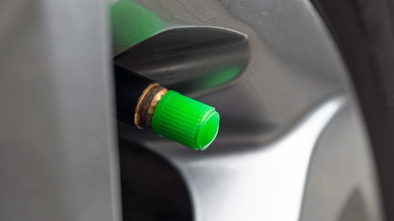 A car tire with a green valve stem cap