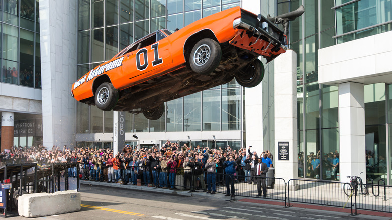 The General Lee making a stunt jump in front of a crowd at a building