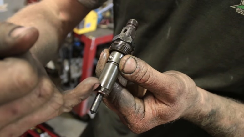 A person holding a diesel fuel injector.