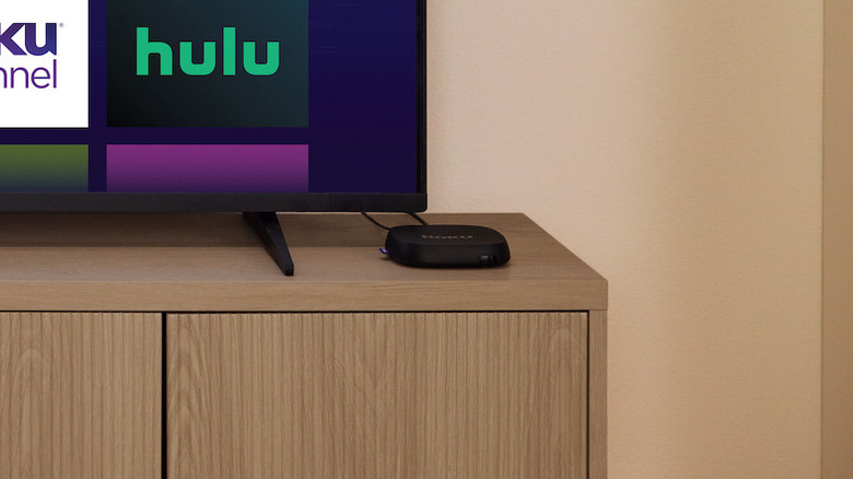 Roku Ultra sitting on top of TV stand with TV next to it