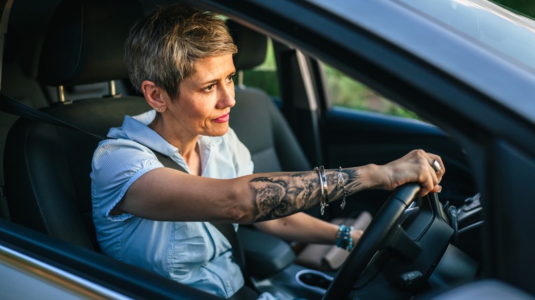 A woman with short hair behind the wheel of a car