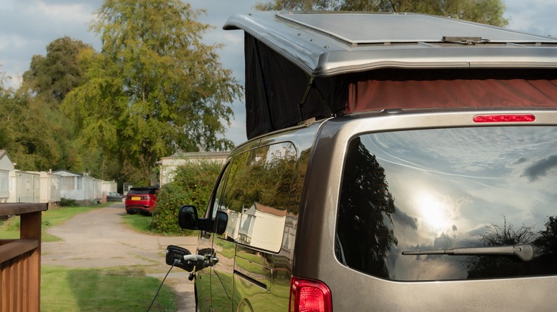 Electric van with extended roof plugged into charger