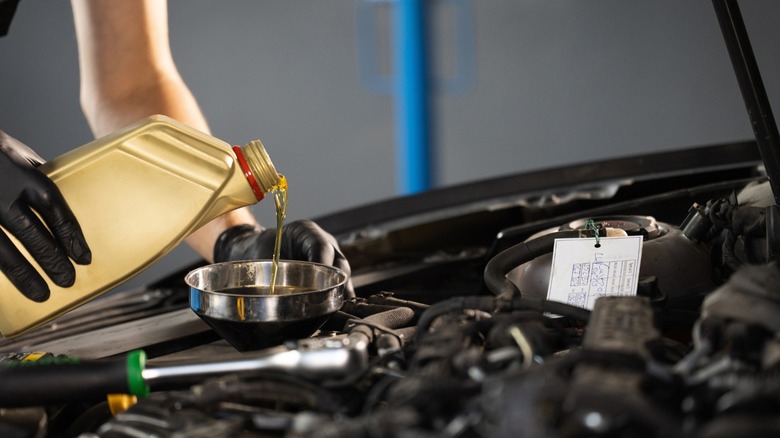 A person pouring oil into their engine's fill port