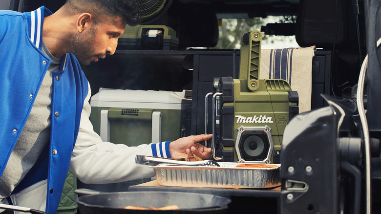 Man adjusting radio in back on vehicle while tailgating