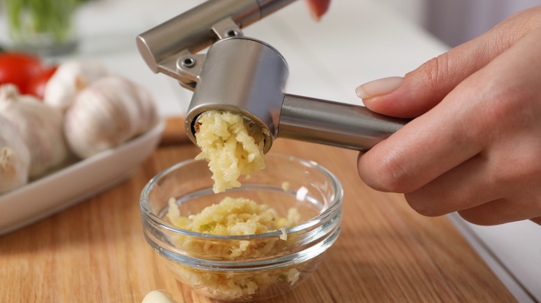 A person using a garlic press to press garlic