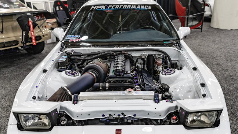 White MK III Toyota Supra with hood removed to show the 2JZ engine