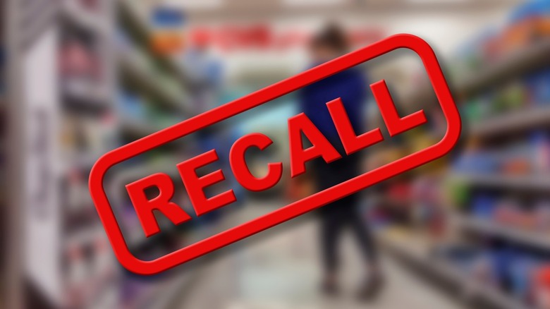 A red recall sign over blurred store shelves