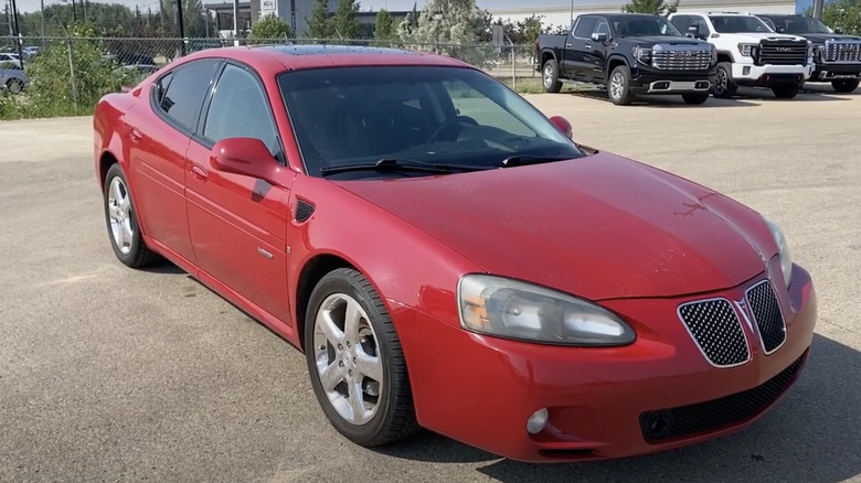 Red Pontiac Grand Prix GZP parked in lot with pickup trucks in background