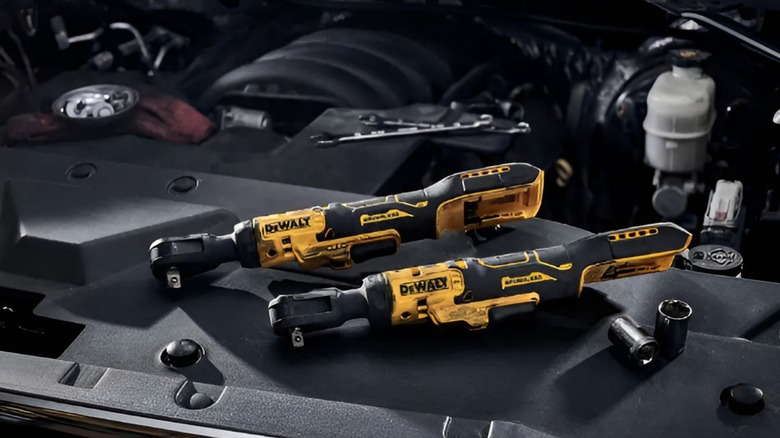 Two DeWalt cordless ratchets sitting above a car's radiator.