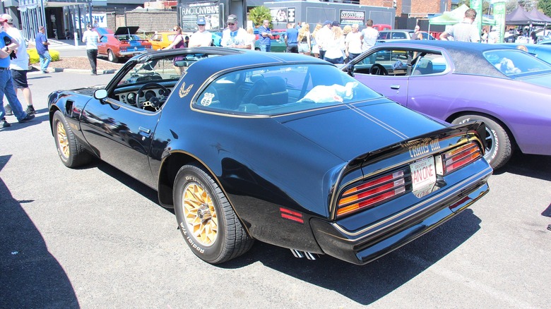 A black 1978 Pontiac Firebird Trans Am SE sporting gold snowflake wheels.