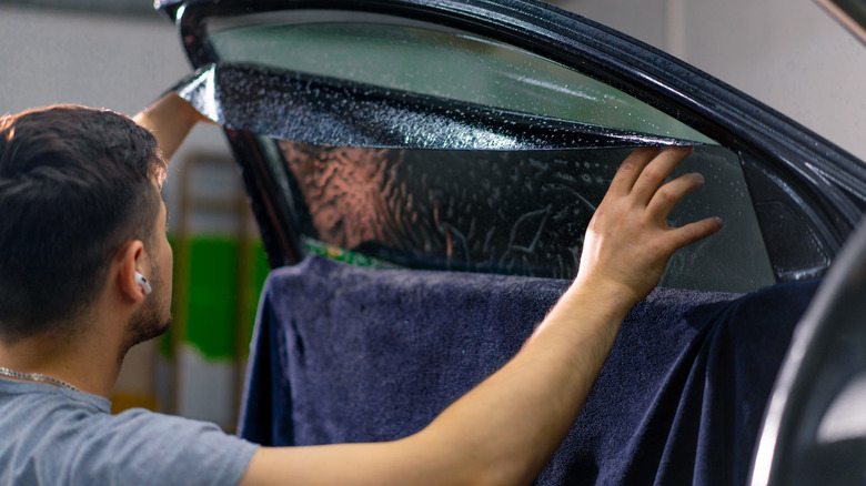 A man appying window tint to a car window