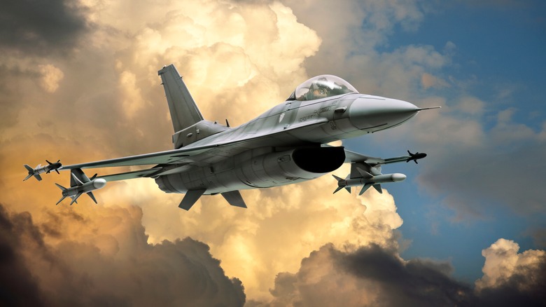 An artist's rendering of an F-16 Fighting Falcon flying over large, colorful clouds