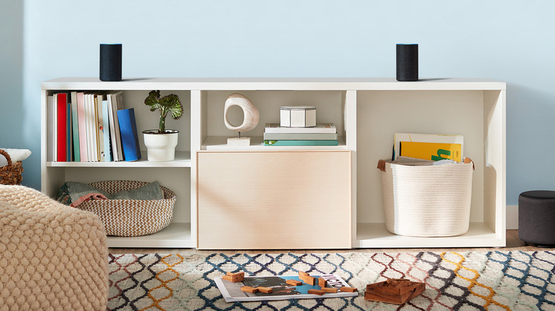 Two Amazon Echo Sub devices on a shelf in a family room