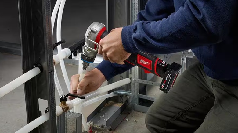 Person using Milwaukee M12 ProPEX expansion tool on pipes