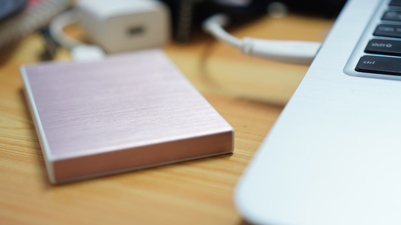 A pink external hard drive connected to a MacBook