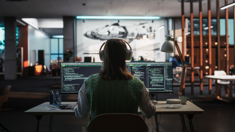 A person works at a desk in front of two computer screens