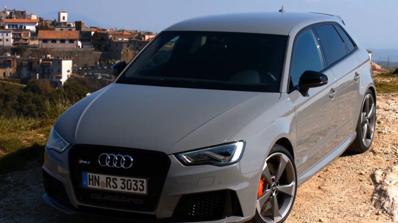 A grey RS3 8V parked on a hill with a town in the background