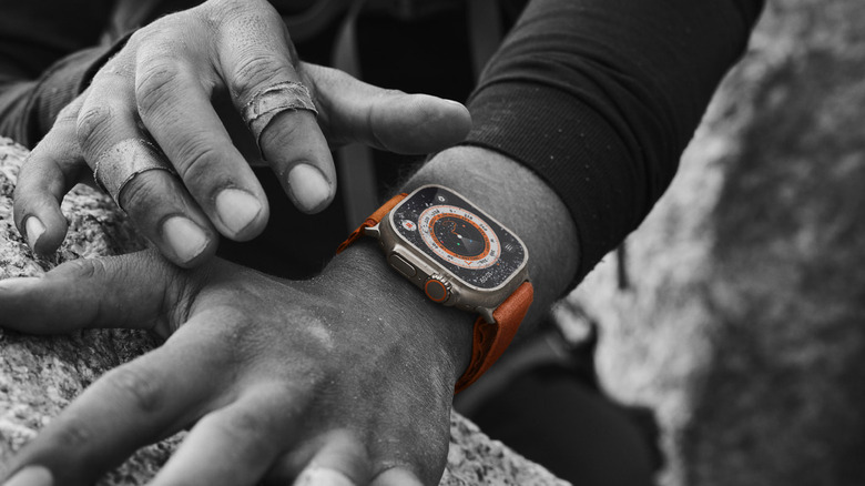 Hand reaching out to touch the orange Apple Watch Ultra