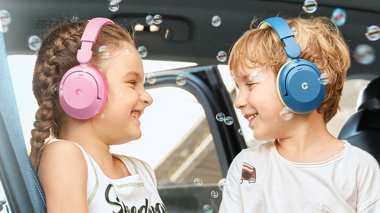 Two children wearing iClever headphones in a car