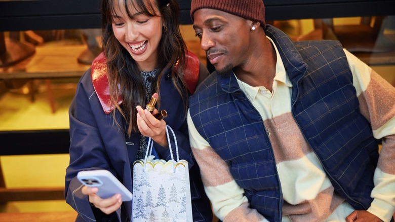 Two people smiling as they look at a phone