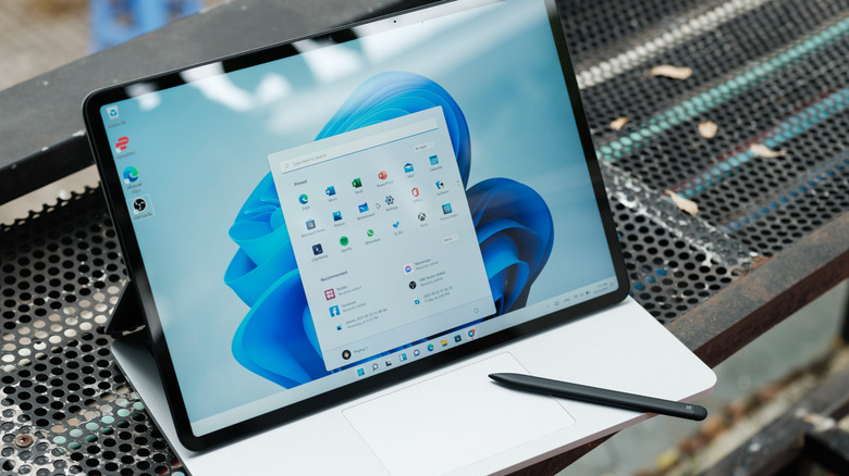 microsoft surface laptop on top of a metal bench shows the start menu