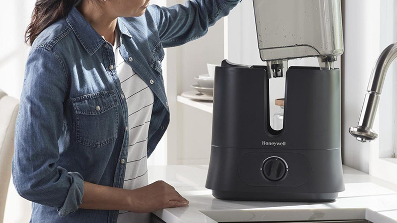 Woman putting the clean water tank back into the Honeywell humidifier