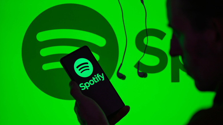 Spotify icon is displayed on a smartphone with Spotify visible in the background