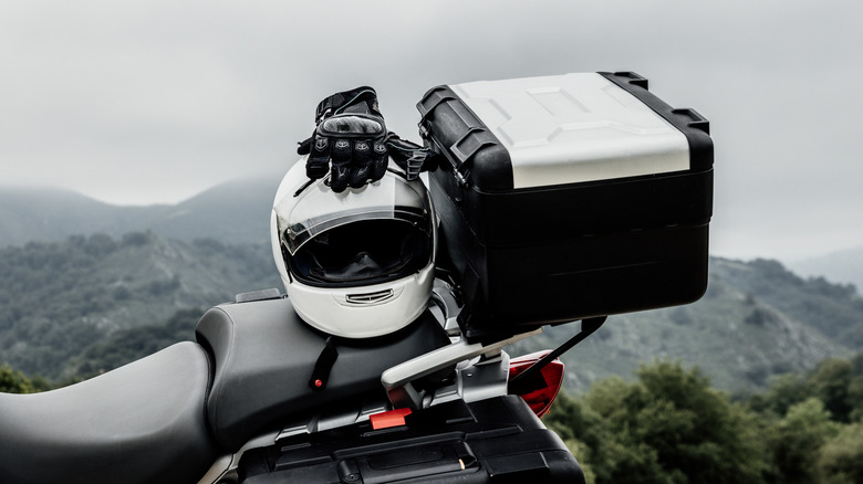 A motorcycle helmet on the back seat of a motorcycle next to hard luggage