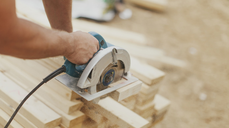 Person using a power saw on various wooden boards