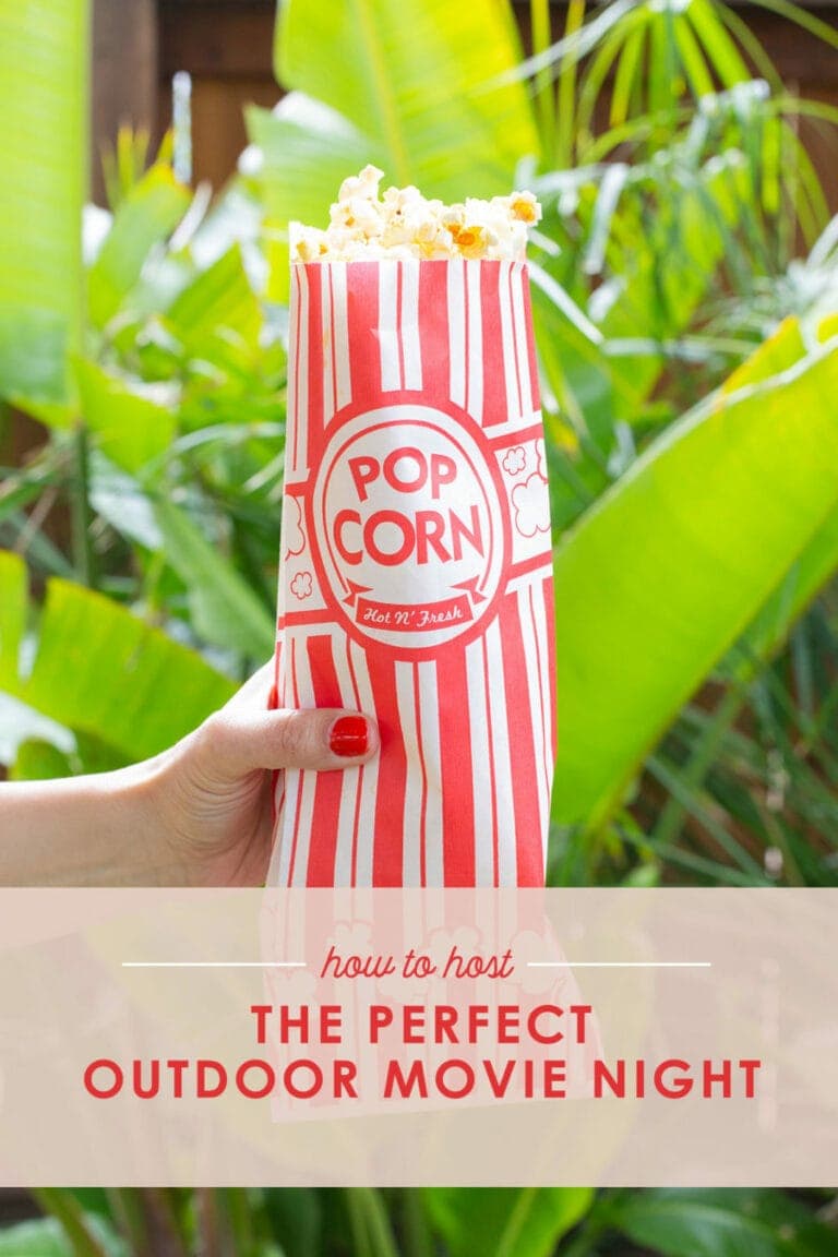 How to host the perfect outdoor movie night, hand holding popcorn bag