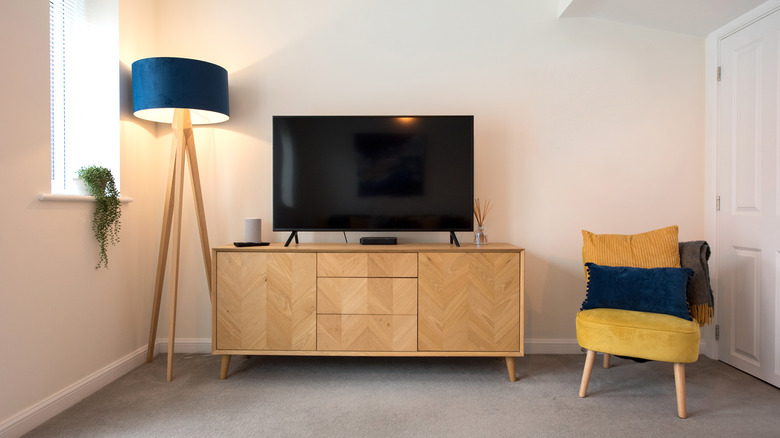 Lounge area featuring a yellow chair and a TV on a dresser