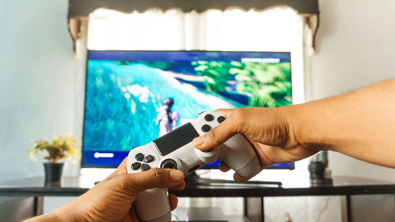 Person holding video game controller in front of TV