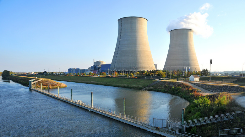 Nuclear power plant beside river with vapor coming out of one smokestack